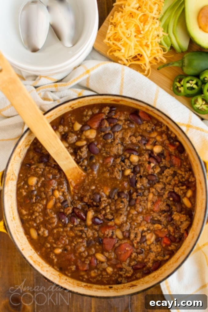 This 3 Bean Chili is made with a homemade chili seasoning, fresh ground beef, fire roasted tomatoes, and three types of canned beans. Great for football!  An overhead shot of a Dutch oven filled with bubbling, rich 3 Bean Chili, ready to be served.