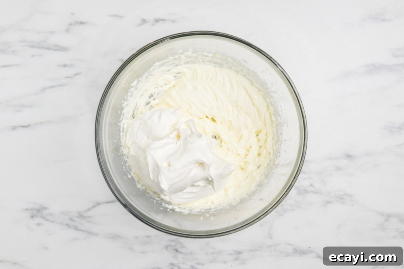 S'mores Lasagna 7 folding cool whip into cream cheese mixture in a bowl