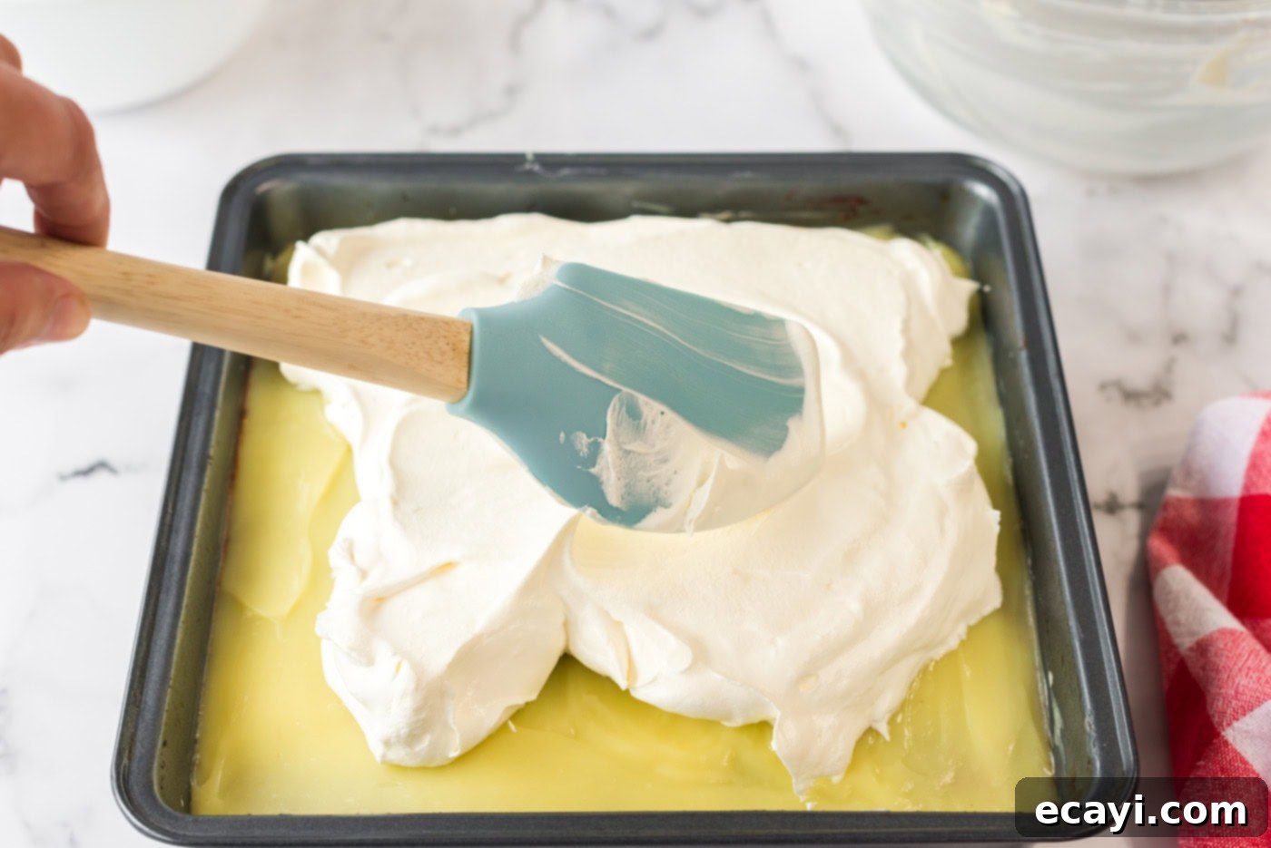 Ultimate Pan Indulgence 12 Cool whip being spread over the vanilla pudding layer