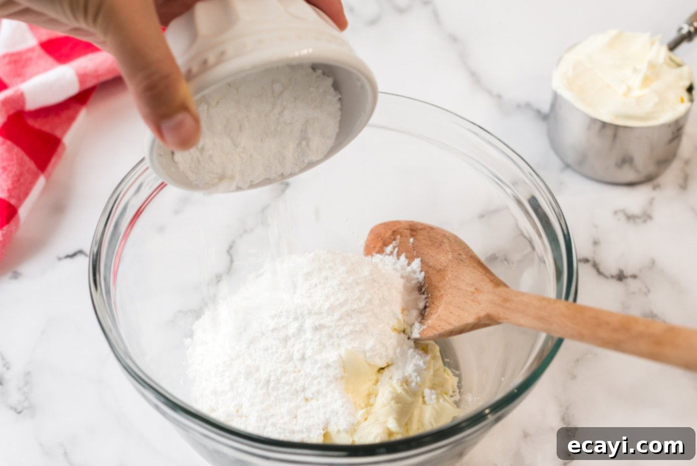 Ultimate Pan Indulgence 7 Powdered sugar being added to a bowl of cream cheese