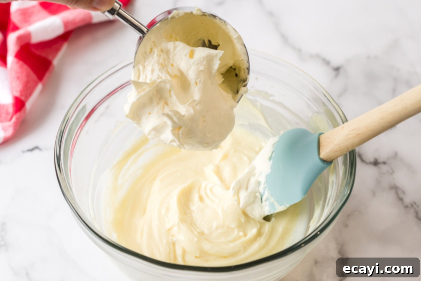 Ultimate Pan Indulgence 8 Cool whip being added to the cream cheese mixture