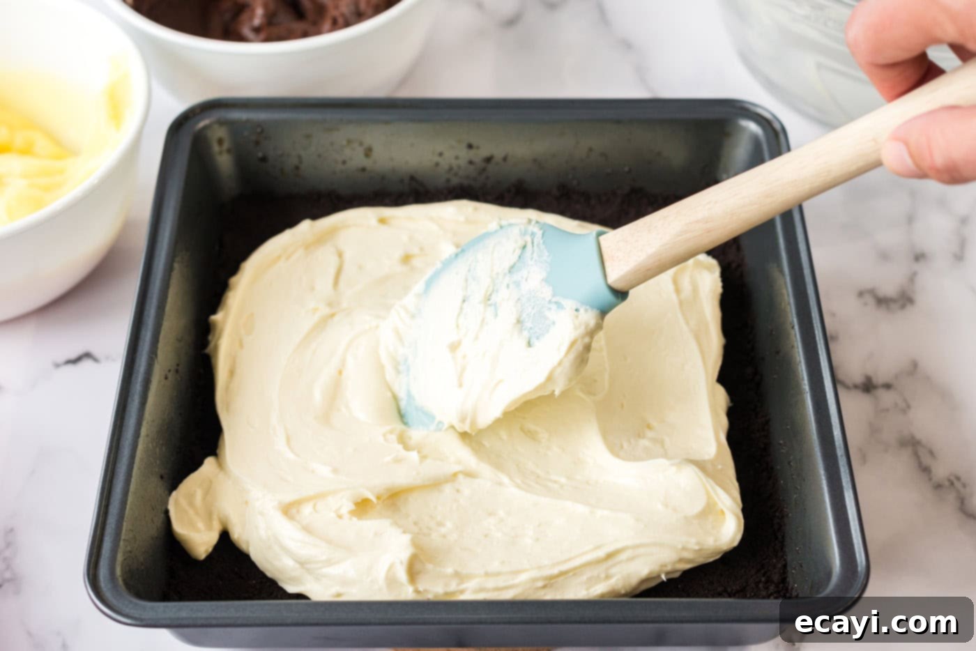Ultimate Pan Indulgence 9 Cream cheese mixture being spread over the crust