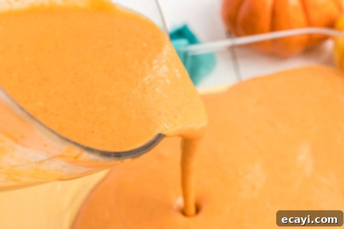 Spiced Pumpkin Magic Cake 5 Pouring the smooth pumpkin pie mixture slowly over the yellow cake batter in the baking pan.