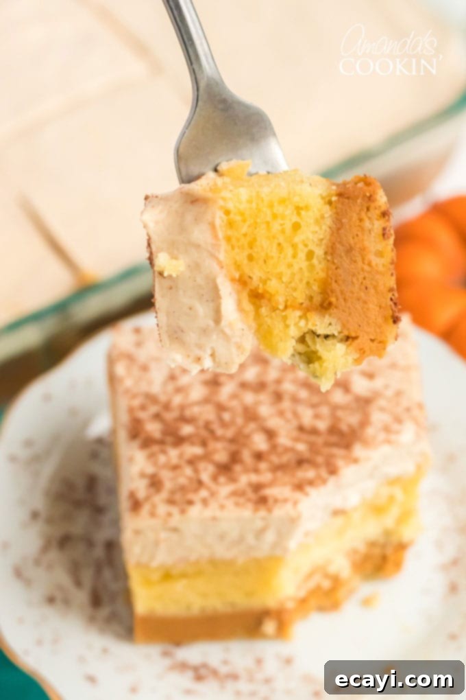 Savor a delicious bite of this effortless pumpkin magic cake, a true fall dessert sensation. A single forkful of pumpkin magic cake showing the distinct layers and creamy topping.