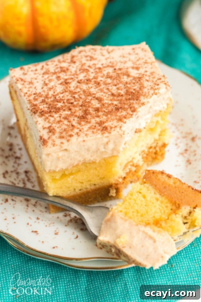 Enjoy a forkful of this incredible pumpkin magic cake, a simplified recipe with a wonderful surprise. A fork taking a bite of pumpkin magic cake, showing the fluffy cake, creamy pumpkin, and whipped topping.