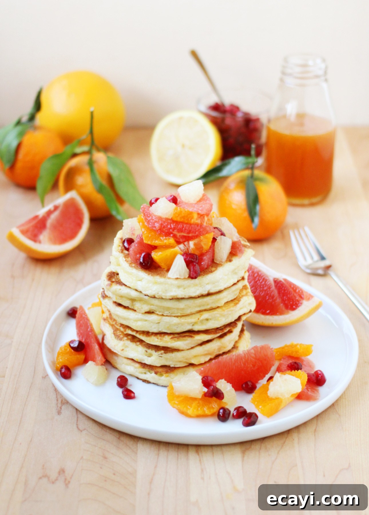 Zesty Ricotta Pancakes with Golden Citrus Drizzle 4 Stack of golden Citrus Ricotta Pancakes topped with fresh grapefruit, orange, and lemon segments, glistening with citrus syrup.