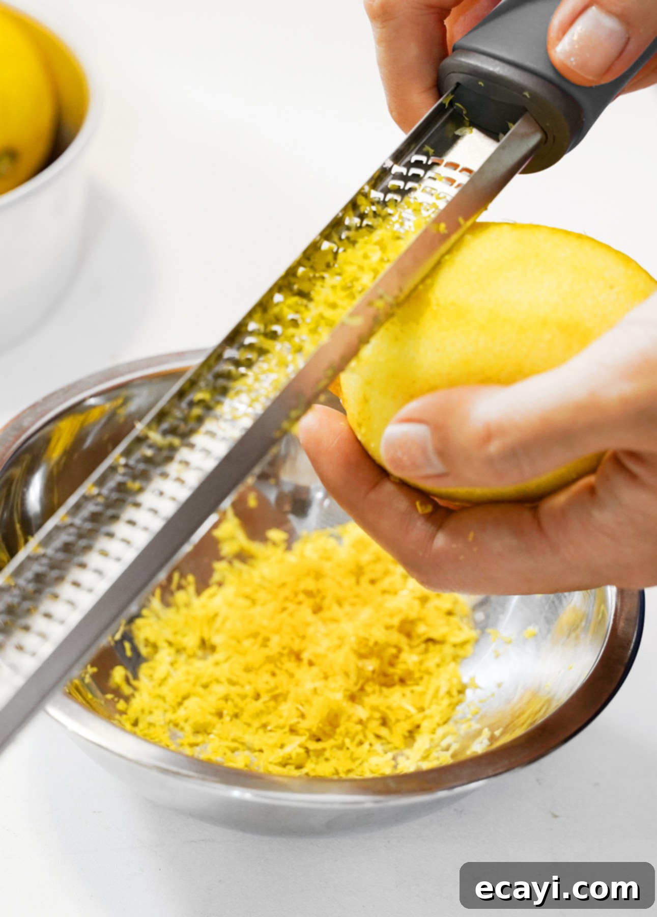 Zesty Ricotta Pancakes with Golden Citrus Drizzle 6 Close-up of a hand zesting a fresh lemon with a Microplane, showcasing the fine zest being collected.