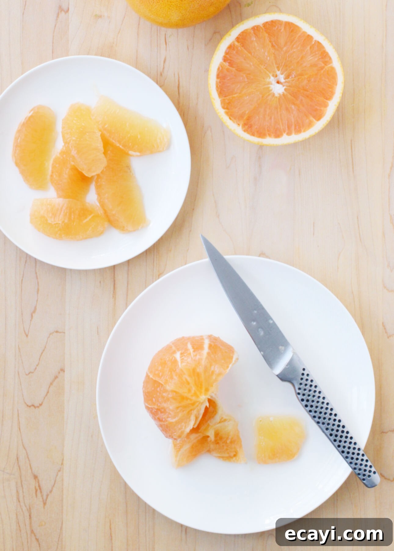 Zesty Ricotta Pancakes with Golden Citrus Drizzle 7 Detailed shot of hands segmenting a pink grapefruit with a knife, demonstrating how to remove the flesh from membranes.