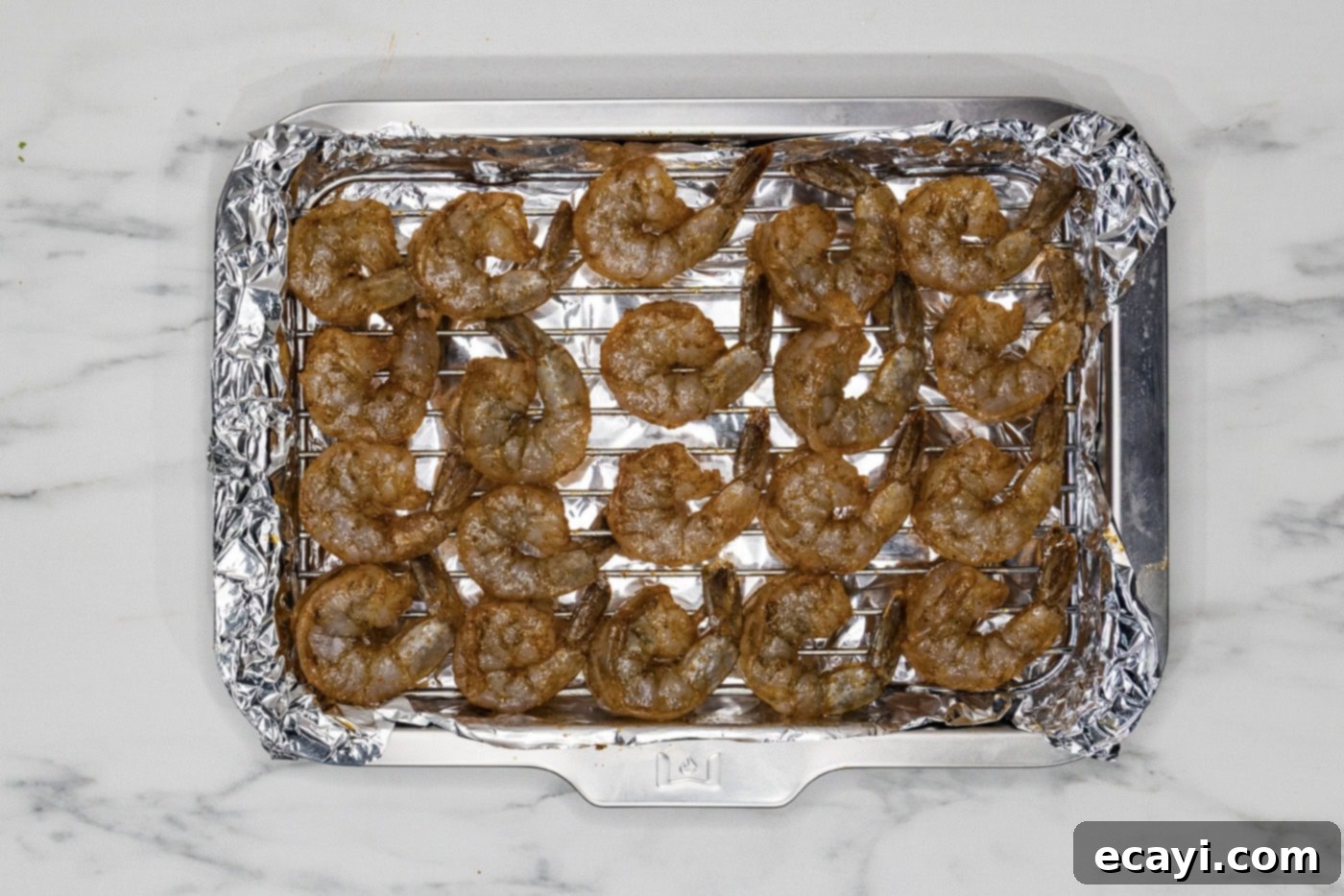Zesty Lemon Broiled Shrimp 6 seasoned shrimp on a foil lined baking sheet with a wire rack