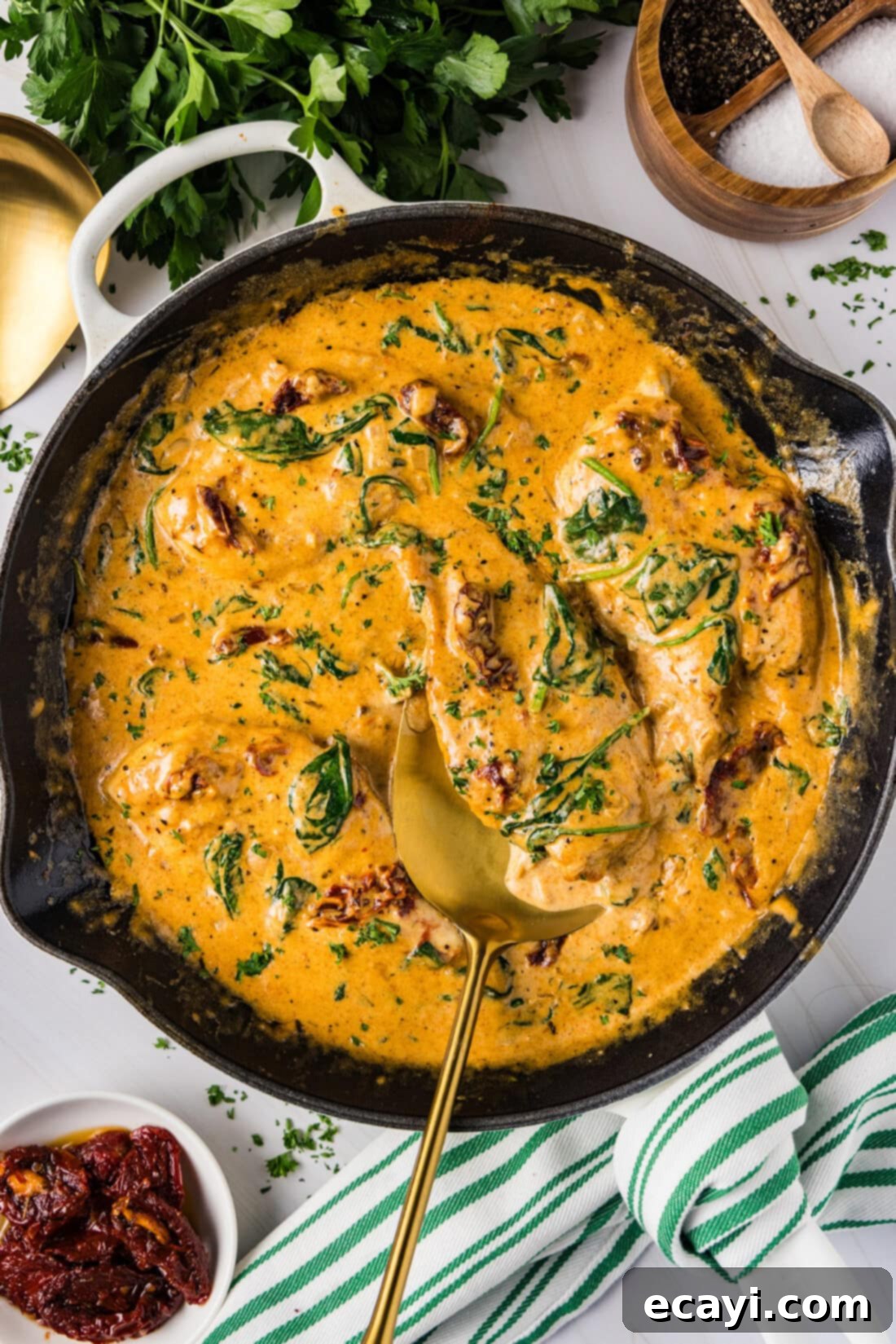 Sun-Kissed Tuscan Chicken 2 Skillet of Creamy Tuscan Chicken with a spatula in it, showcasing tender chicken, spinach, and sun-dried tomatoes in a rich sauce.