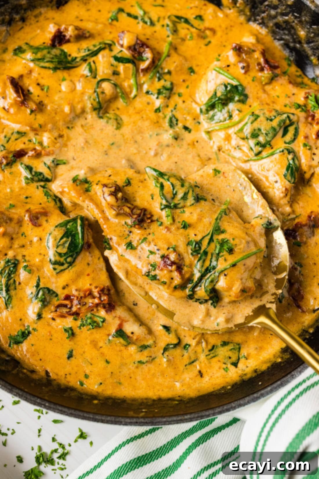 Sun-Kissed Tuscan Chicken 3 Close up photo of a spatula serving Creamy Tuscan Chicken from a skillet, highlighting the texture and richness of the sauce.