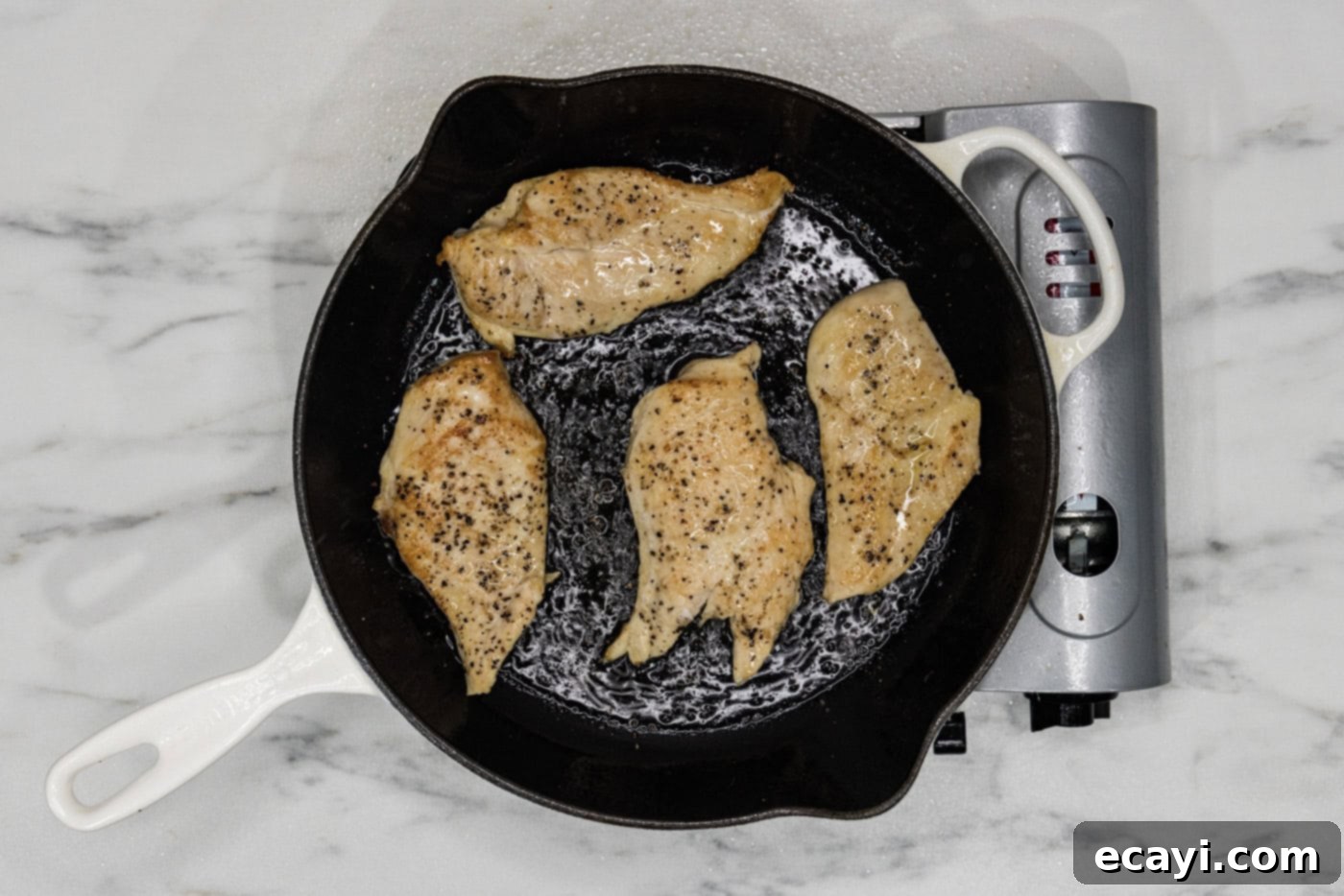 Sun-Kissed Tuscan Chicken 5 Cooked chicken breasts seared to a golden brown in a skillet, ready to be removed.