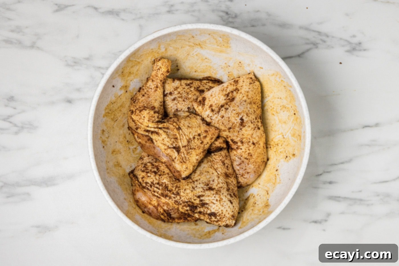 Juicy Smoked Chicken Quarters 5 raw chicken quarters in a bowl with wet rub
