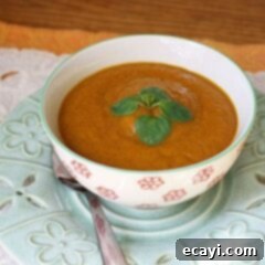 Cozy Slow Cooker Pumpkin Soup 7 A close up photo of a bowl of creamy pumpkin soup, garnished with parsley.