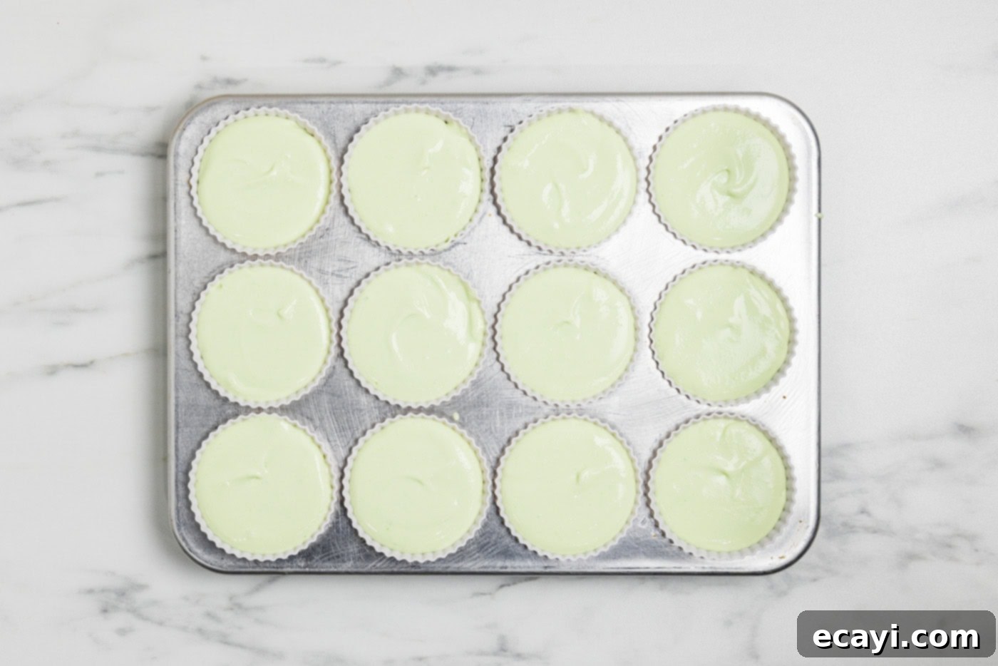Tangy Keto Lime Cheesecake Minis 7 overhead photo of cheesecake mixture in silicone baking cups inside a muffin pan