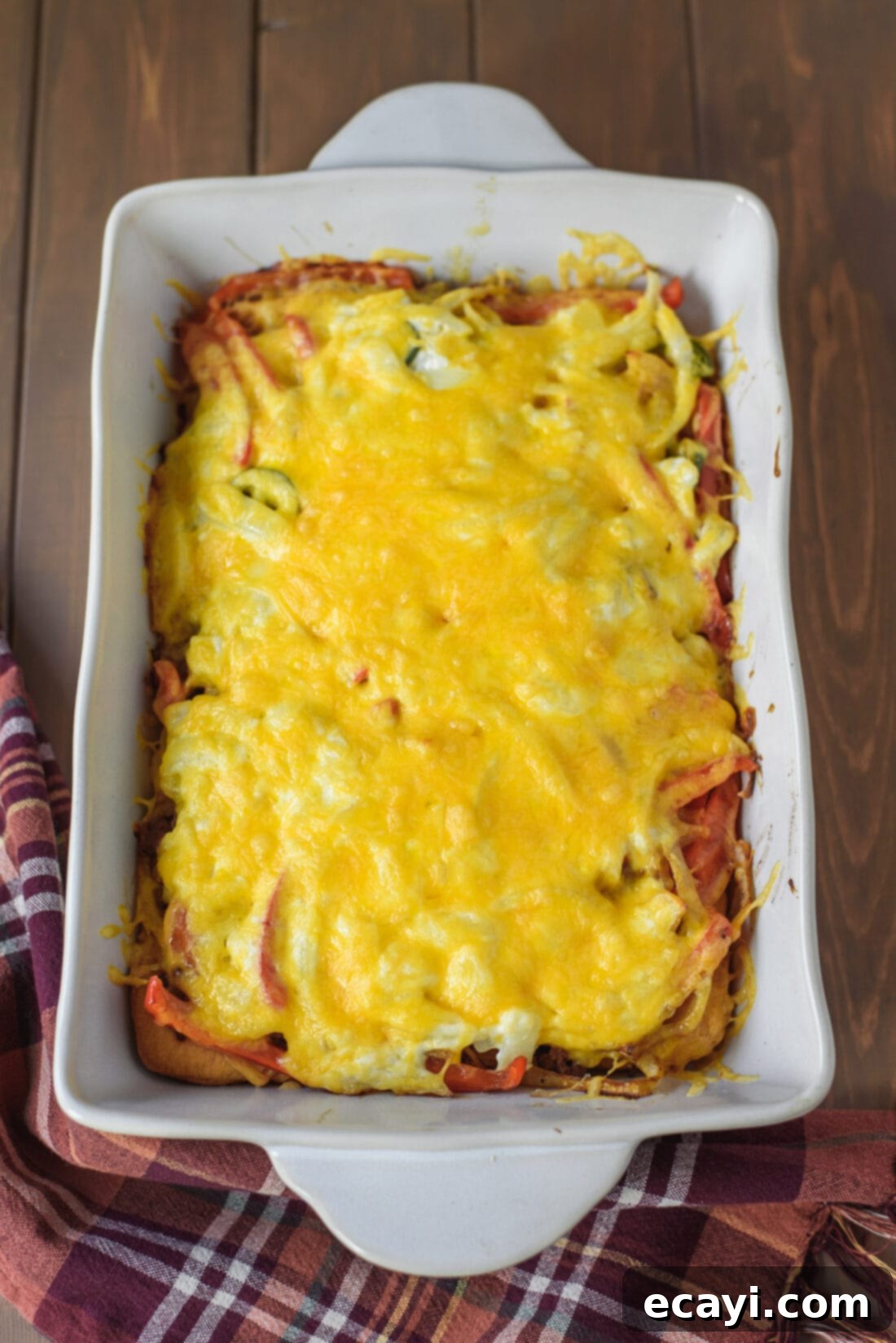 The ultimate John Wayne Casserole, fresh out of the oven, with perfectly melted cheese! A freshly baked John Wayne Casserole in a 13x9 inch pan, with bubbly, melted cheese and a golden biscuit crust.