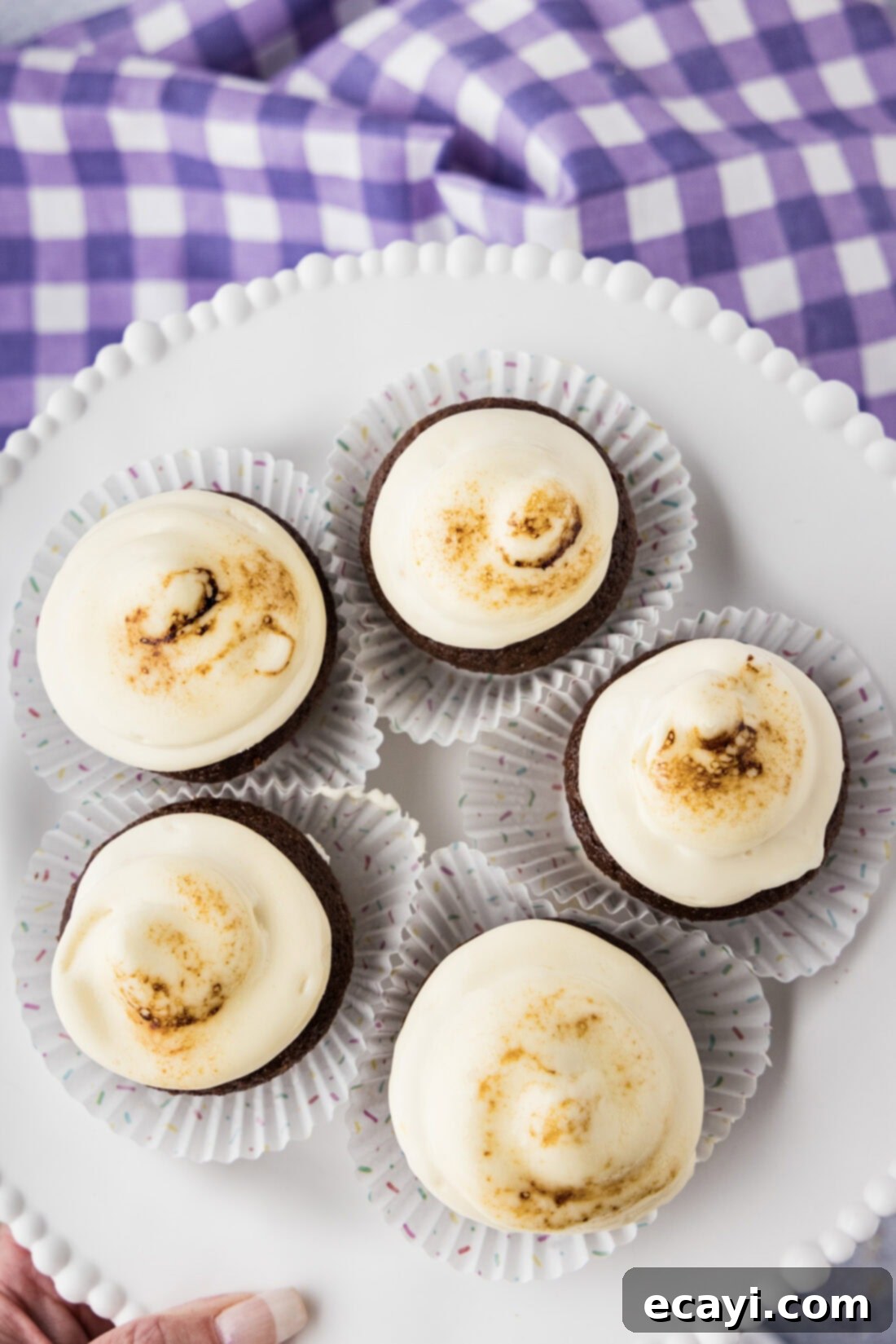 Heavenly Mallow Fluff 11 Cupcakes frosted with marshmallow frosting, with one partially browned and melted from a kitchen torch.
