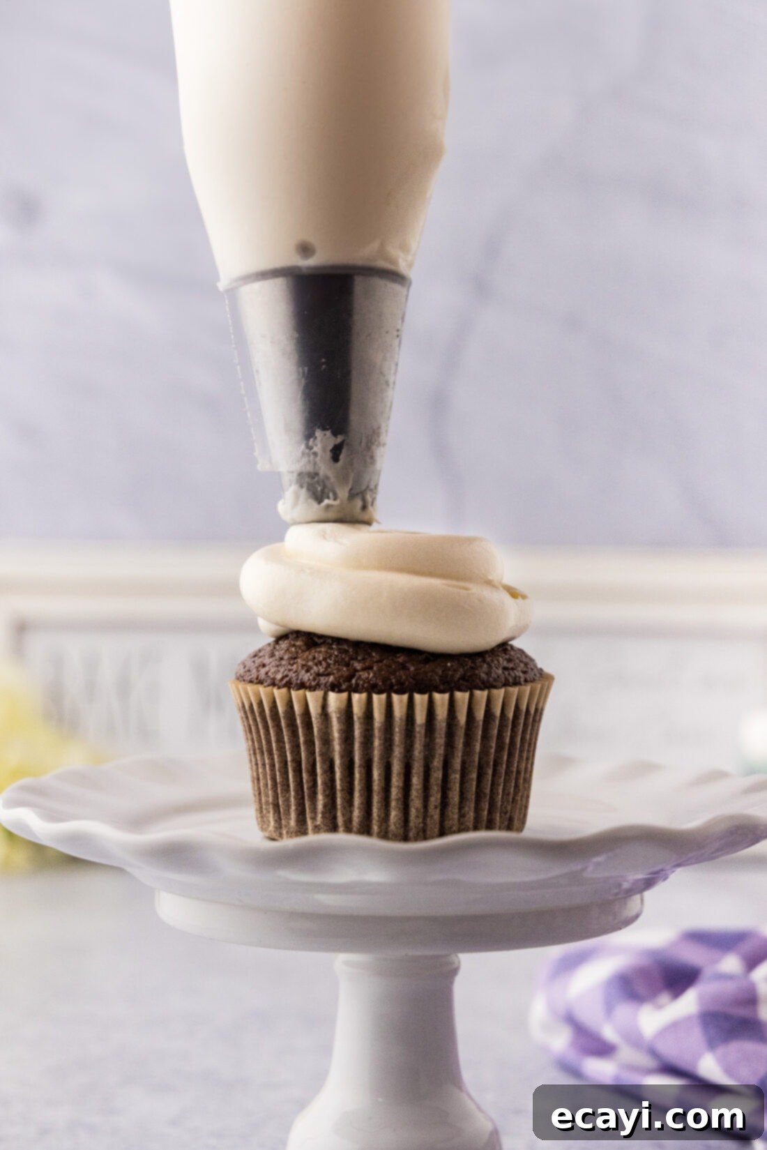 Heavenly Mallow Fluff 3 Marshmallow frosting being skillfully piped onto a freshly baked cupcake with a decorative tip.