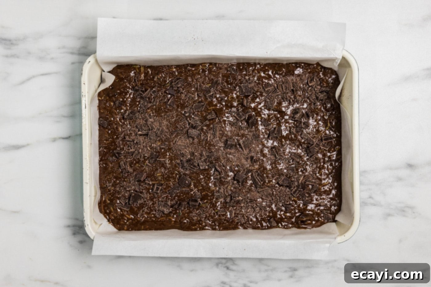 Hidden Veggie Fudge 11 Zucchini brownie batter in a pan with chopped chocolate sprinkled on top for extra richness