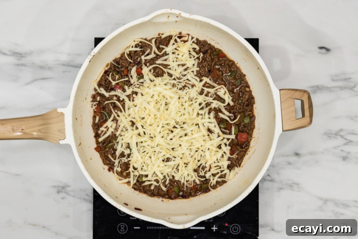 Philly Cheesesteak Messy Melts 8 Shredded provolone cheese melting into the hot philly cheesesteak sloppy joe mixture in a skillet