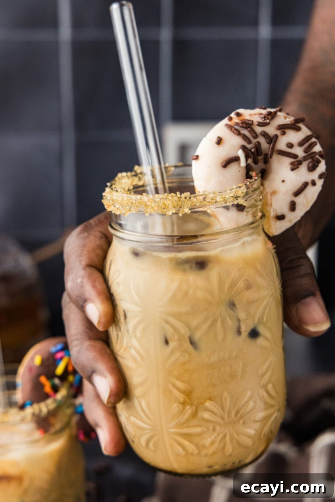 Velvet Espresso Chill 3 A hand gracefully holding up a tall glass of Iced Espresso Cocktail, highlighting its layered beauty and inviting chilled texture.