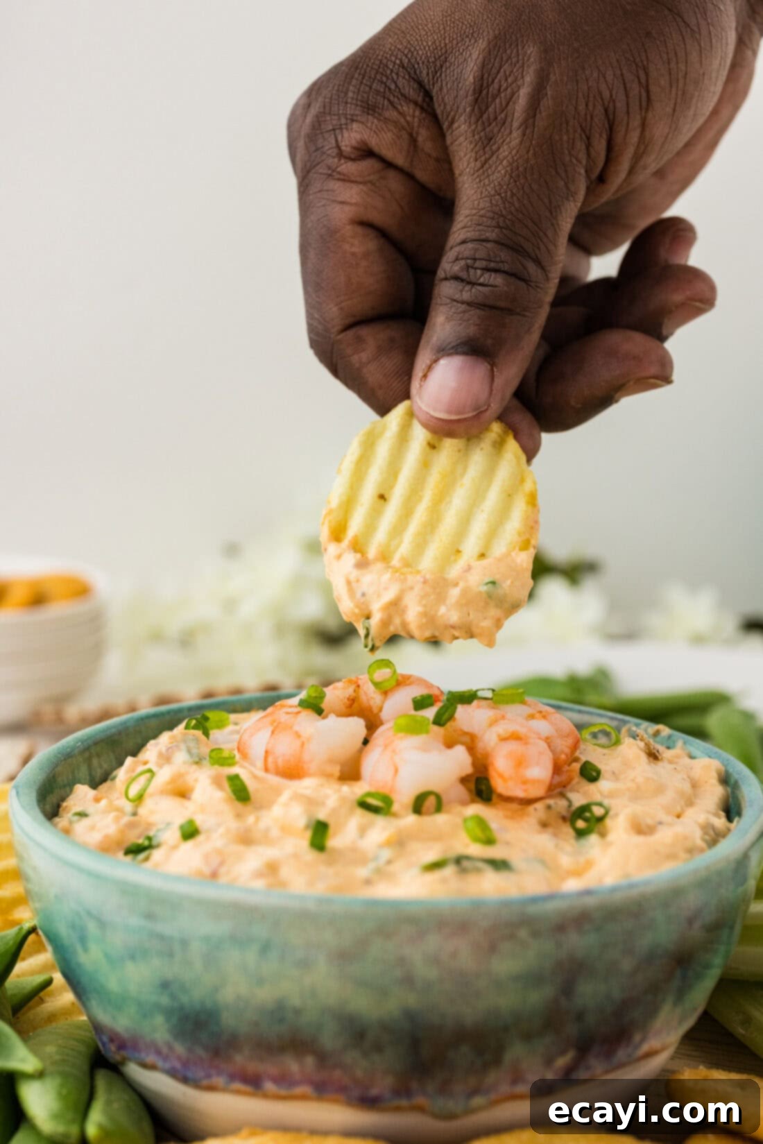 Creamy Shrimp Delight 3 Hand holding a chip with a generous scoop of homemade cold shrimp dip on it
