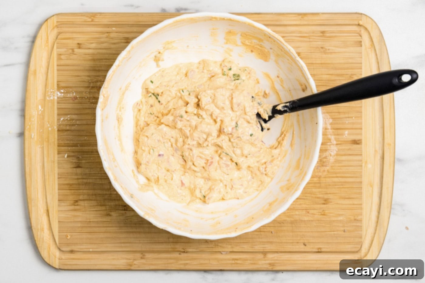 Creamy Shrimp Delight 9 Rubber spatula in a bowl of mixed shrimp dip, ready to be chilled