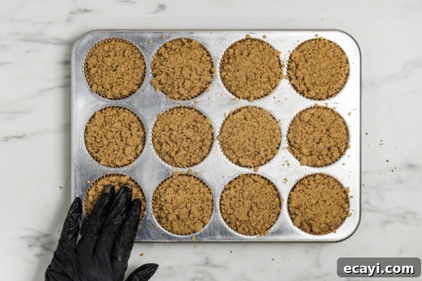 Spiced Apple Muffins 11 hand pressing down on streusel topping on top of muffin batter