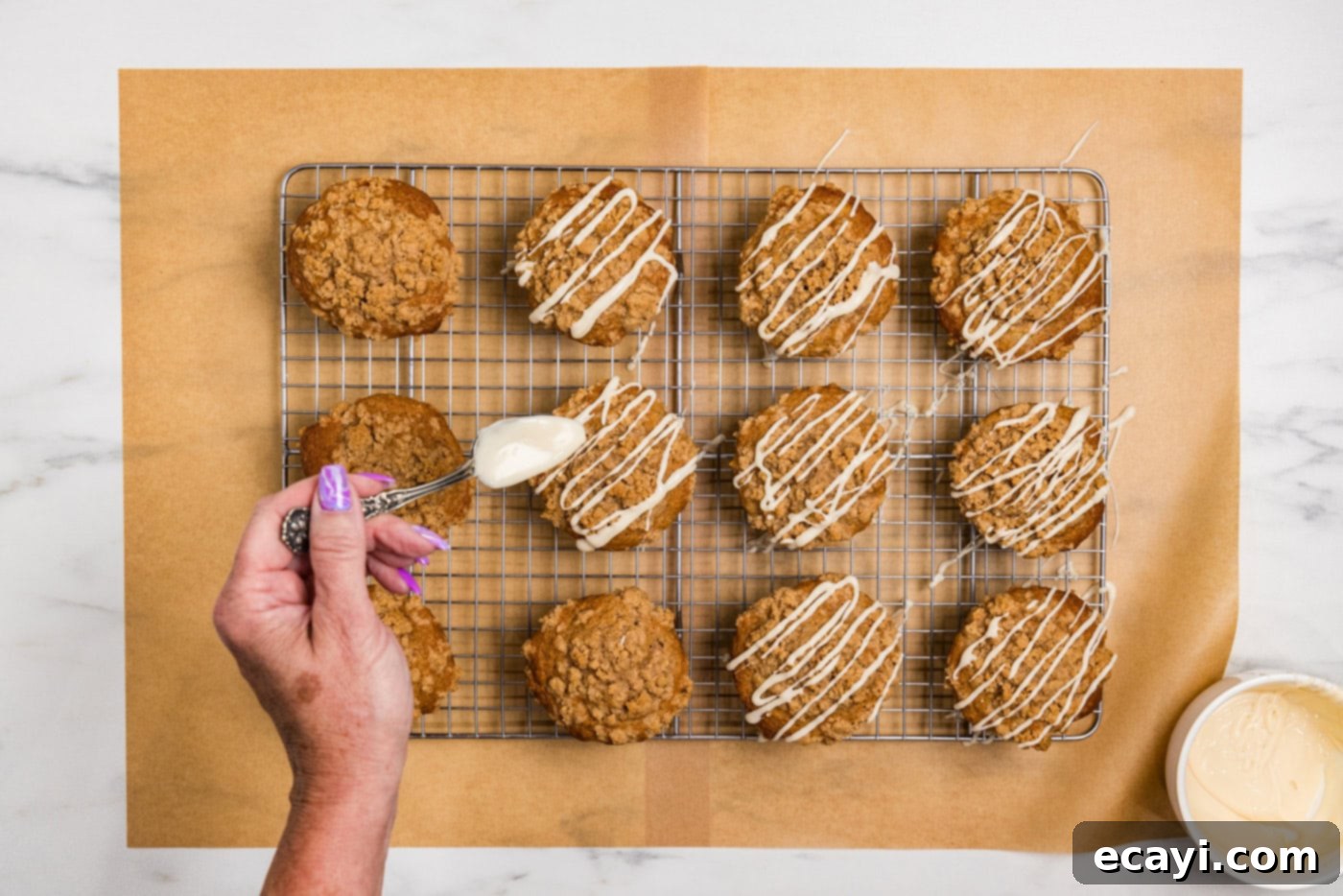 Spiced Apple Muffins 13 hand drizzling glaze on top of apple streusel muffins