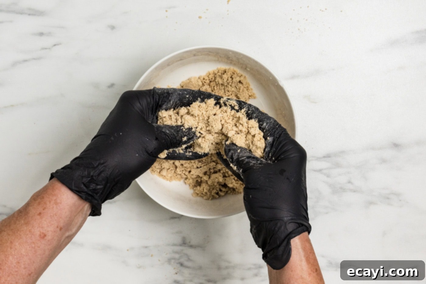 Spiced Apple Muffins 9 gloved hands squeezing streusel ingredients together in a bowl