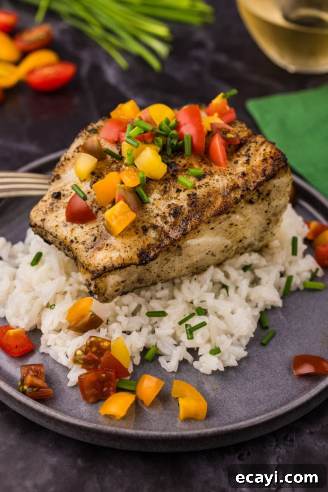 Buttery Grilled Chilean Sea Bass 3 Close-up of grilled Chilean sea bass fillet on a bed of white rice, garnished with fresh herbs, ready to be served.