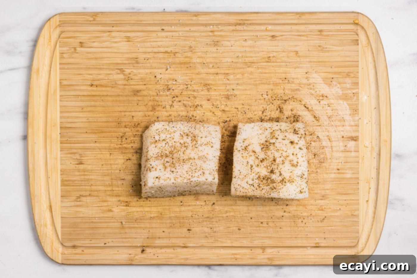 Buttery Grilled Chilean Sea Bass 6 Raw Chilean sea bass fillets seasoned with Old Bay and garlic salt, ready for grilling.