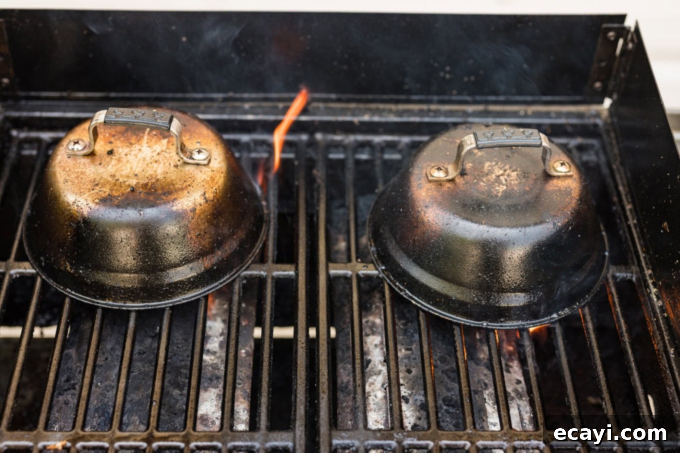 Buttery Grilled Chilean Sea Bass 8 Metal basting covers placed over Chilean sea bass fillets on a hot grill, steaming as they cook.