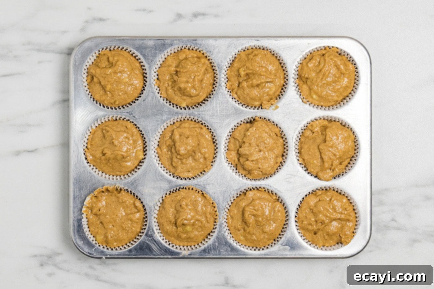 Golden Harvest Pumpkin Banana Muffins 11 Muffin liners filled to the brim with pumpkin banana muffin batter, ready for baking