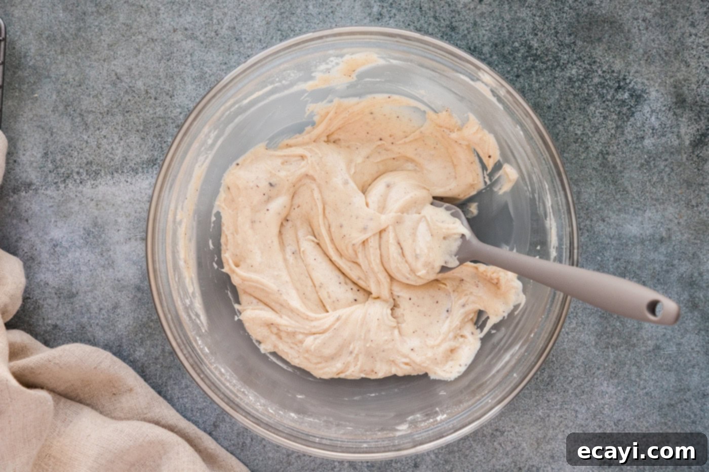 Spiced Apple Cider Pound Cake 13 Smooth brown butter glaze in a mixing bowl, being stirred with a rubber spatula.