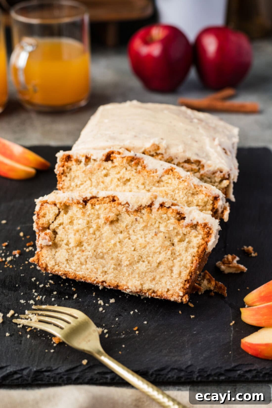 Spiced Apple Cider Pound Cake 14 Two slices of Apple Cider Pound Cake, perfectly glazed, resting beside the loaf with a fork, ready for a bite.