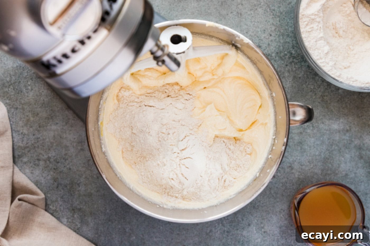 Spiced Apple Cider Pound Cake 9 Dry ingredients being gently folded into the wet batter in a stand mixer bowl during the mixing process.