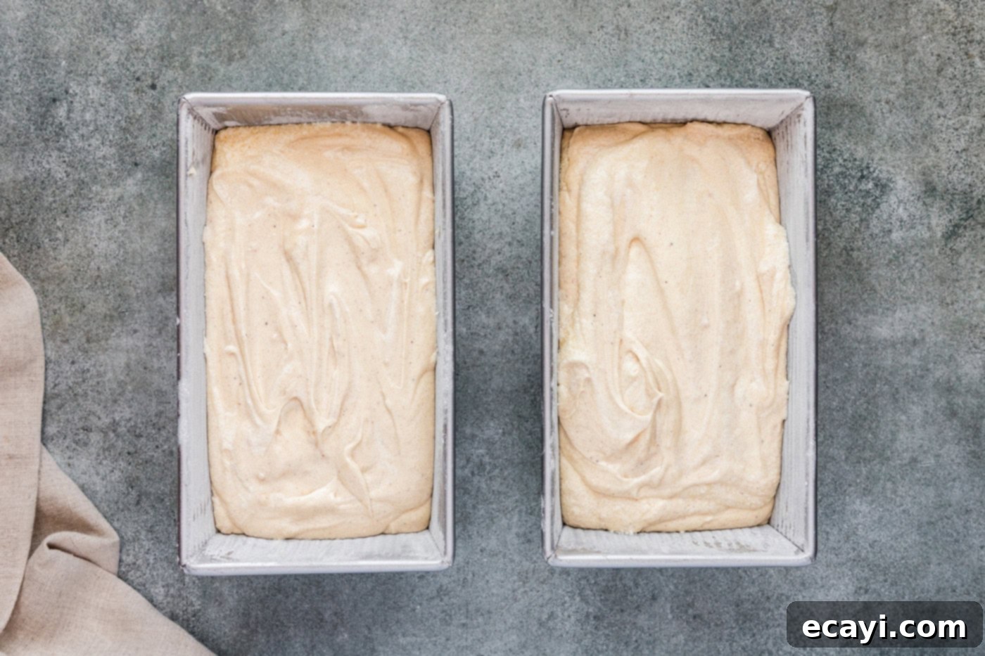 Spiced Apple Cider Pound Cake 10 Smooth apple cider pound cake batter evenly distributed in two loaf pans, ready for baking.