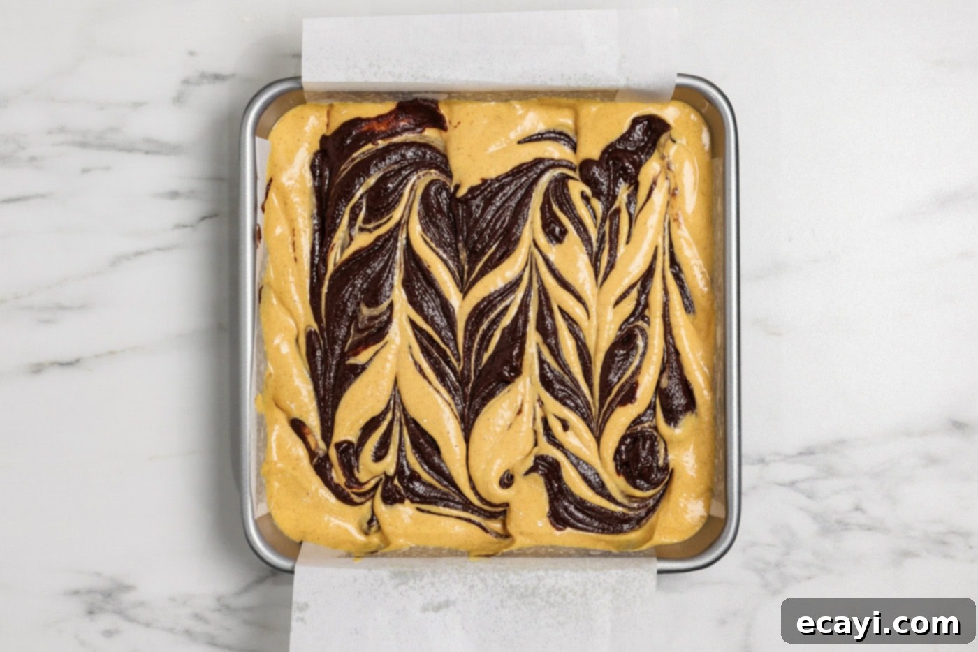 Spiced Pumpkin Cheesecake Swirl Brownies 15 swirls of brownie batter on top of pumpkin cheesecake batter in a pan