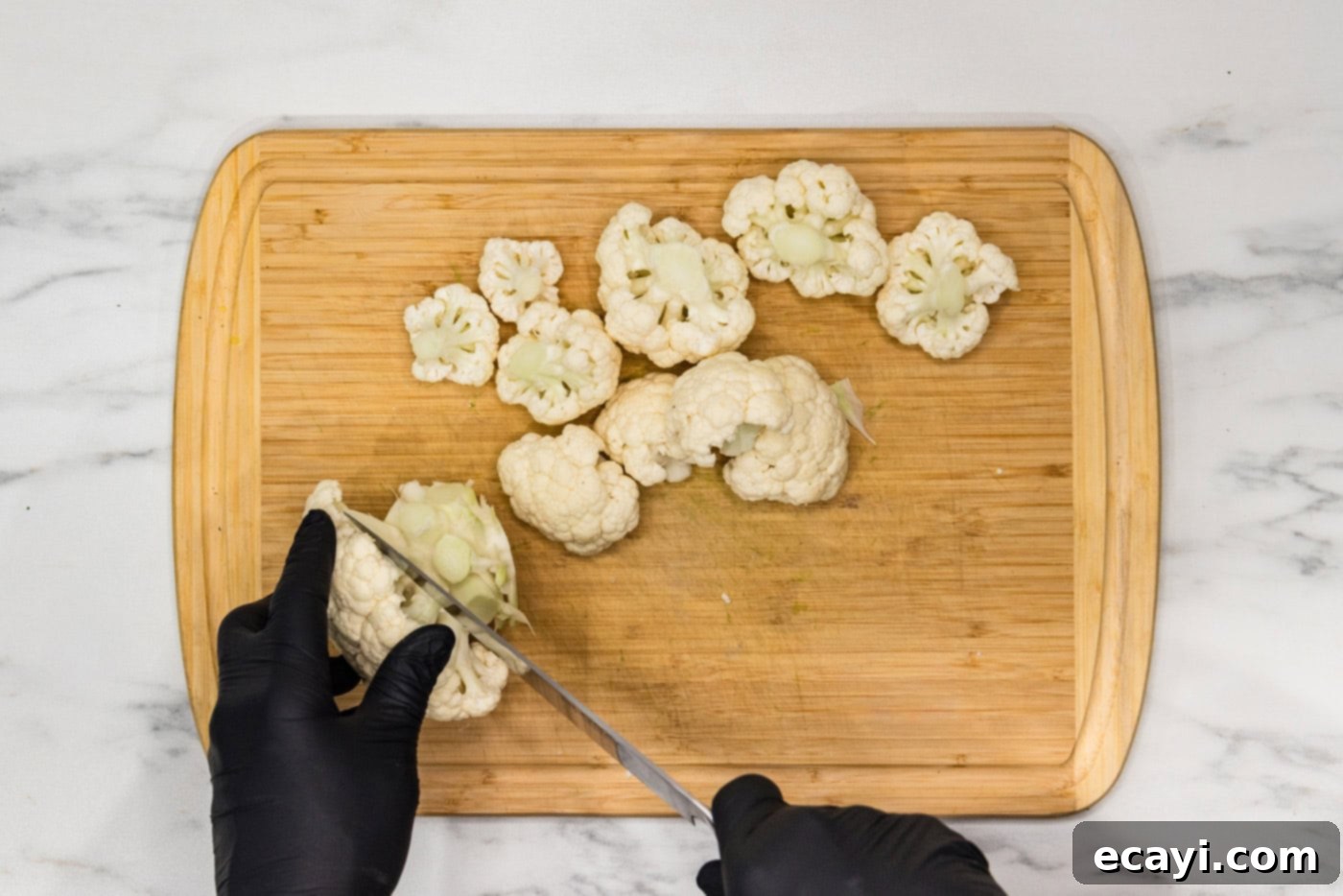 Crispy Air Fried Cauliflower 5 Hand using a knife on a cutting board to cut cauliflower head into florets
