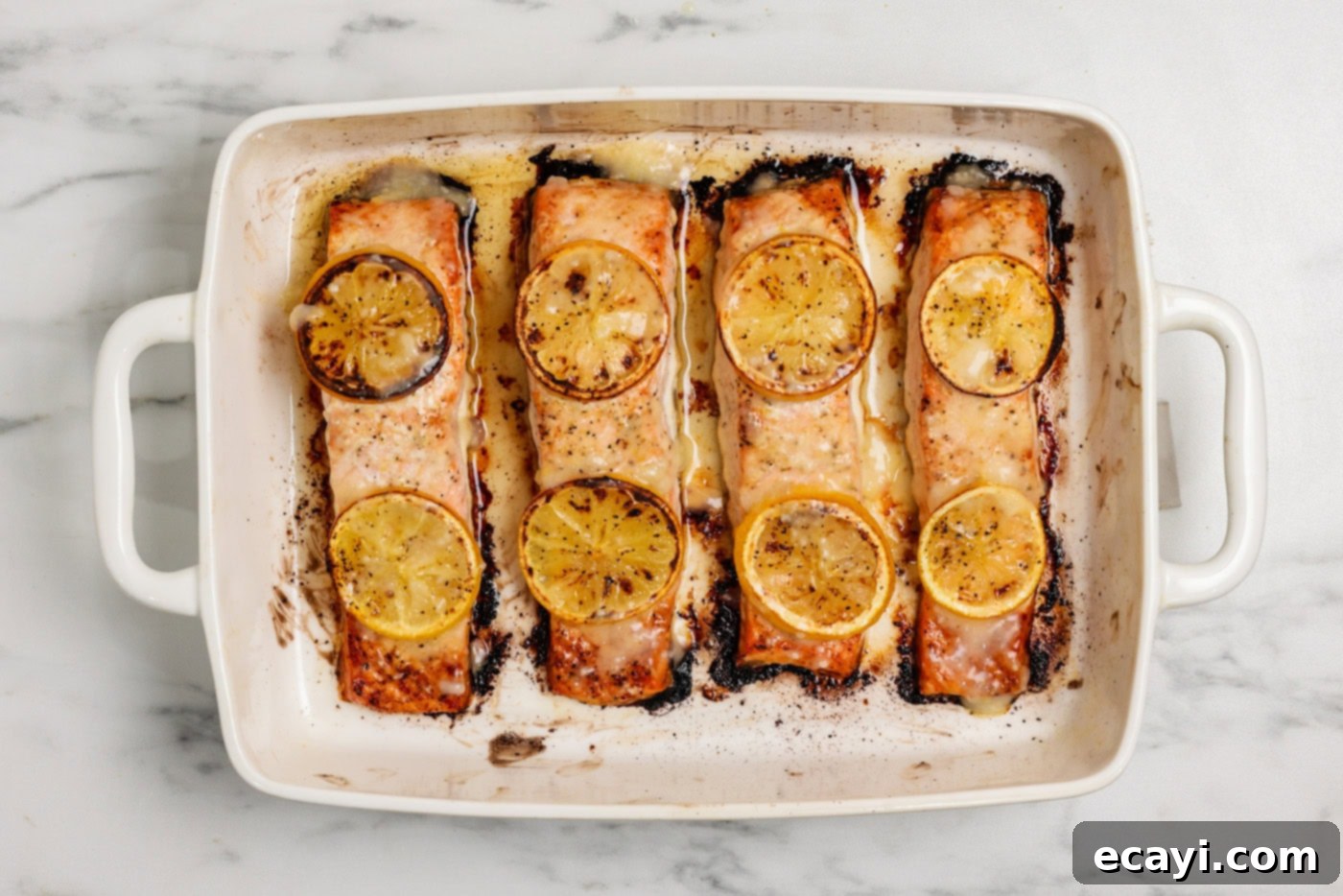 Zesty Lemon Salmon Bake 8 Overhead shot of beautifully baked lemon salmon arranged in a baking sheet, ready to be served, highlighting its appealing presentation.