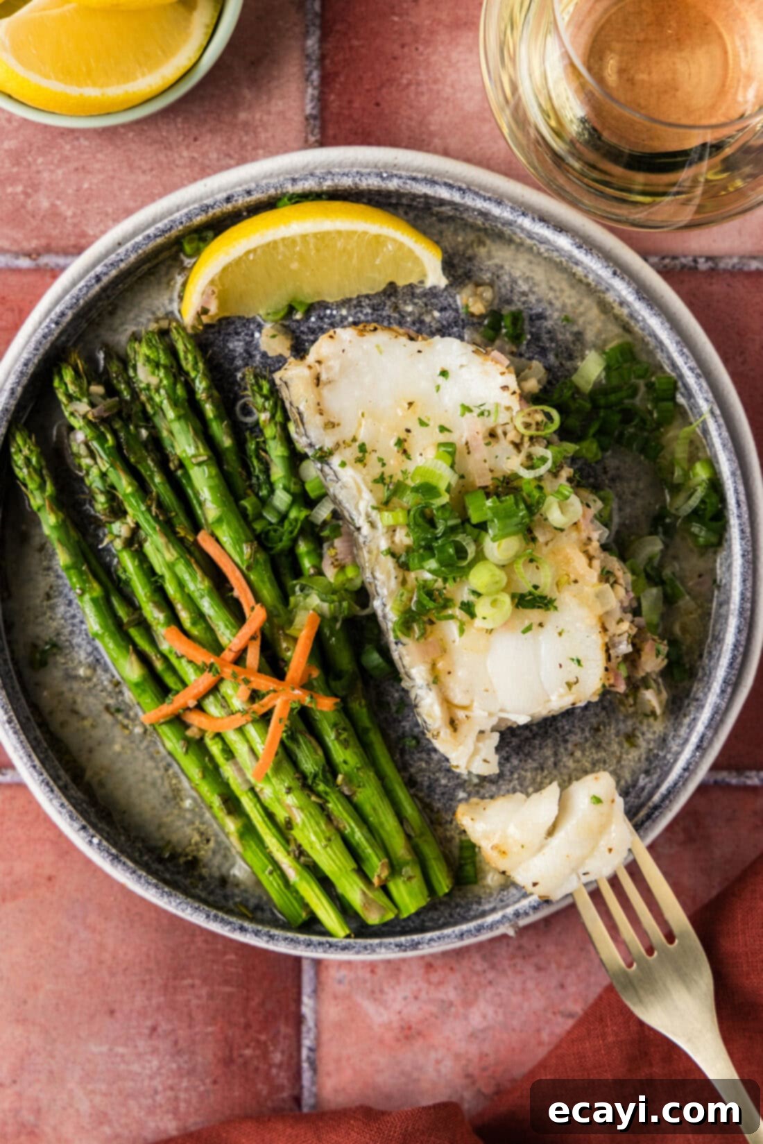 Coastal Elegance: Steamed Chilean Sea Bass 2 Steamed Chilean Sea Bass on a plate broken apart by a fork, showcasing its flaky texture.