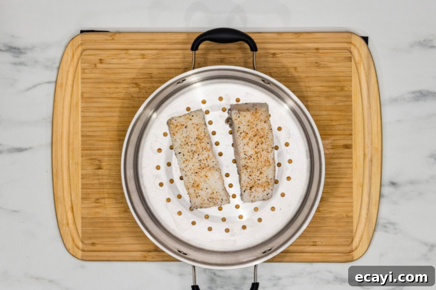 Coastal Elegance: Steamed Chilean Sea Bass 5 Seasoned Chilean sea bass fillets neatly arranged in a steamer basket, ready for cooking.