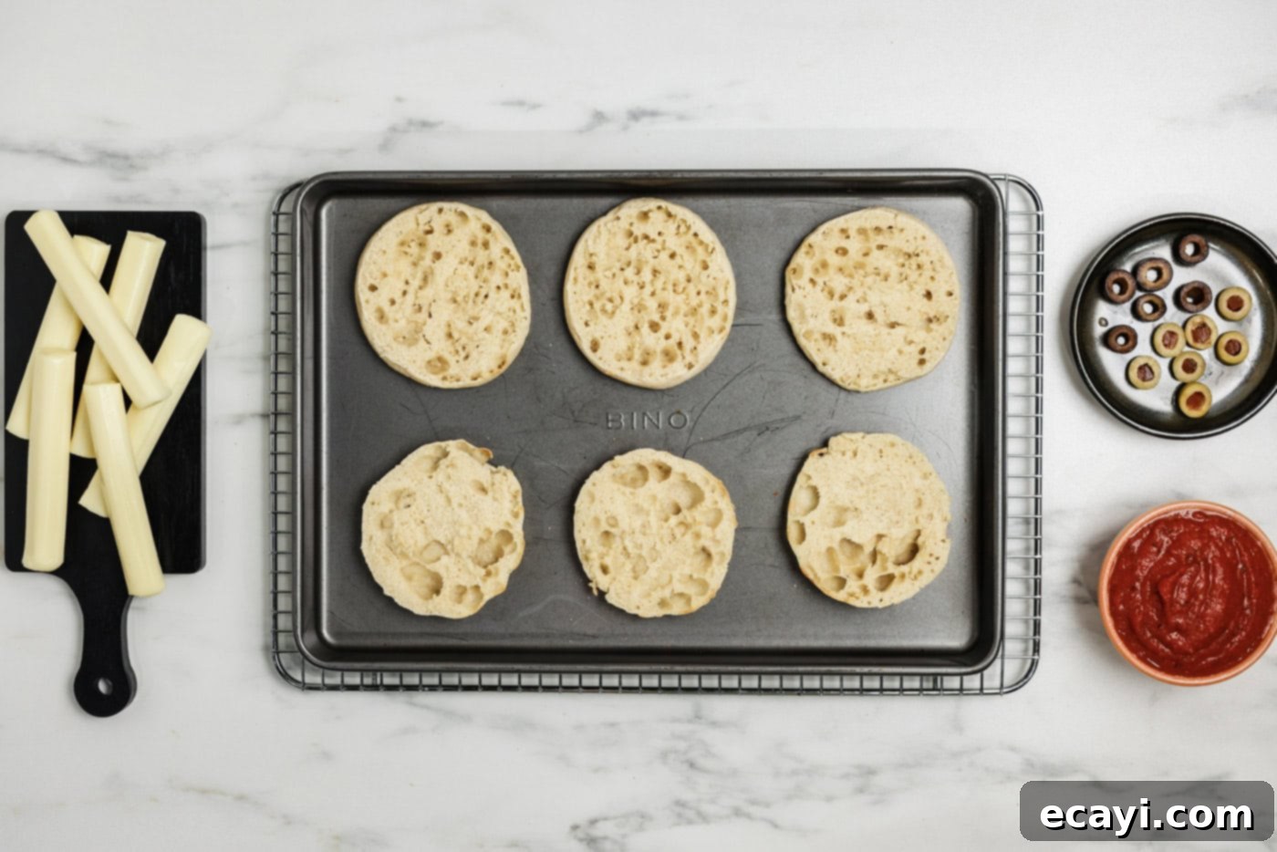 Mummy Mini Pizza Bites 5 toasted English muffins on a baking sheet