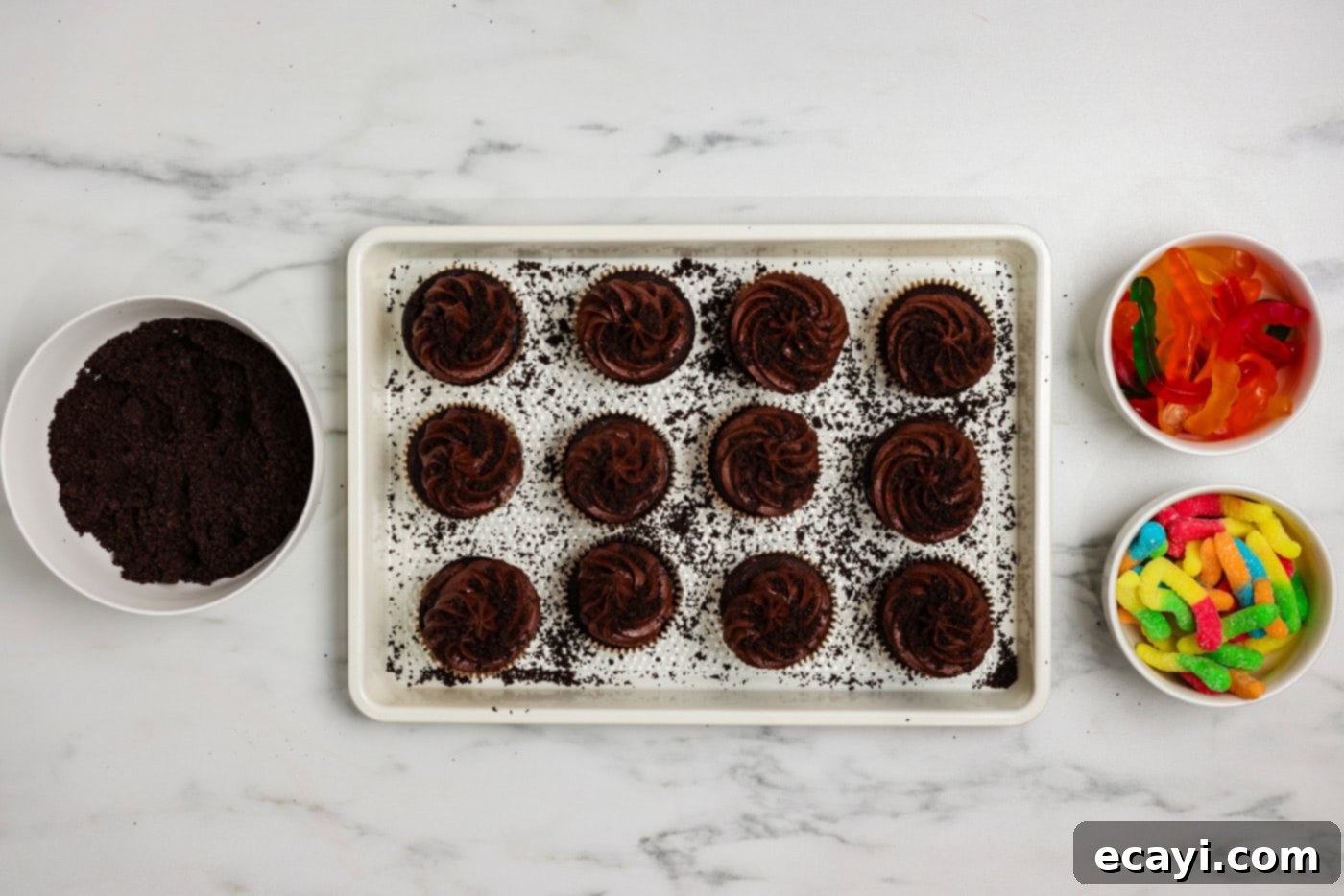 Graveyard Crumble Cups 9 Crushed Oreos sprinkled over chocolate frosted cupcakes on a baking sheet