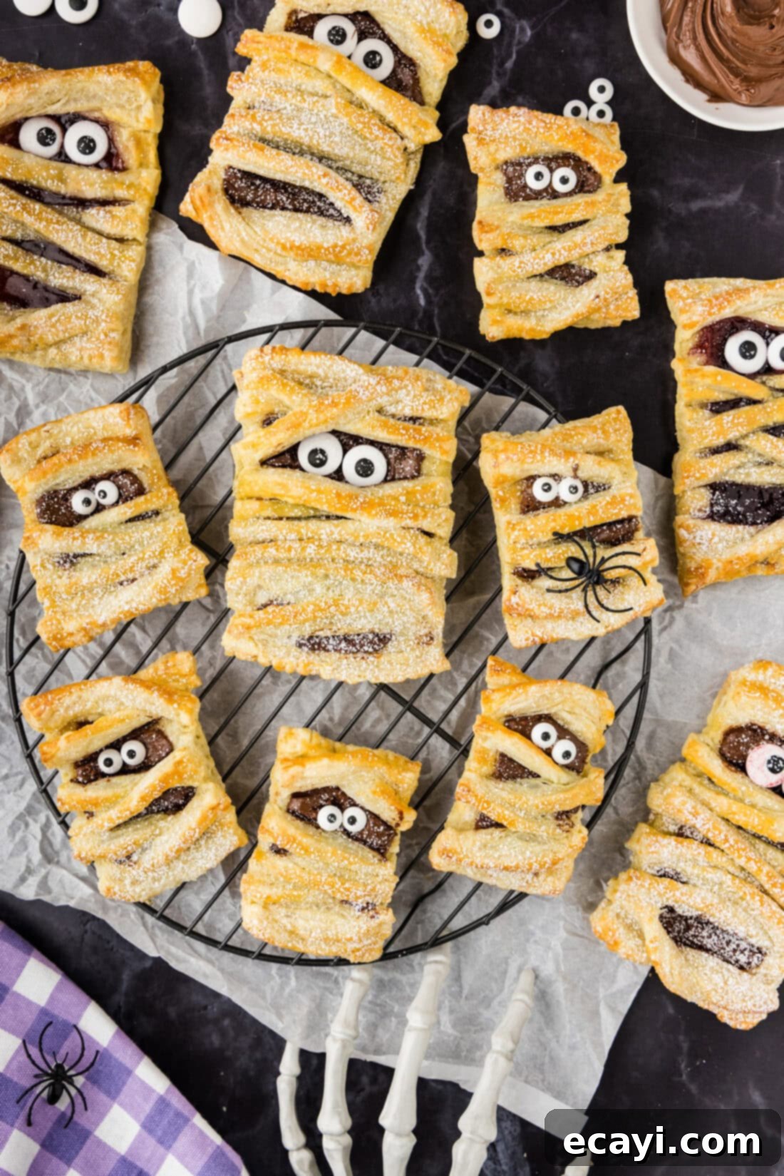 Halloween Mummy Bites 5 Mummy Hand Pies resting on a wire rack, dusted with powdered sugar.