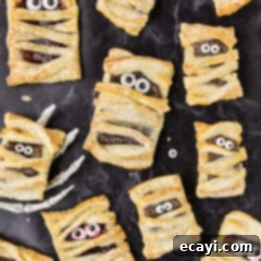 Halloween Mummy Bites 6 Mummy Hand Pies with one resting in a skeleton hand, set against a spooky backdrop.