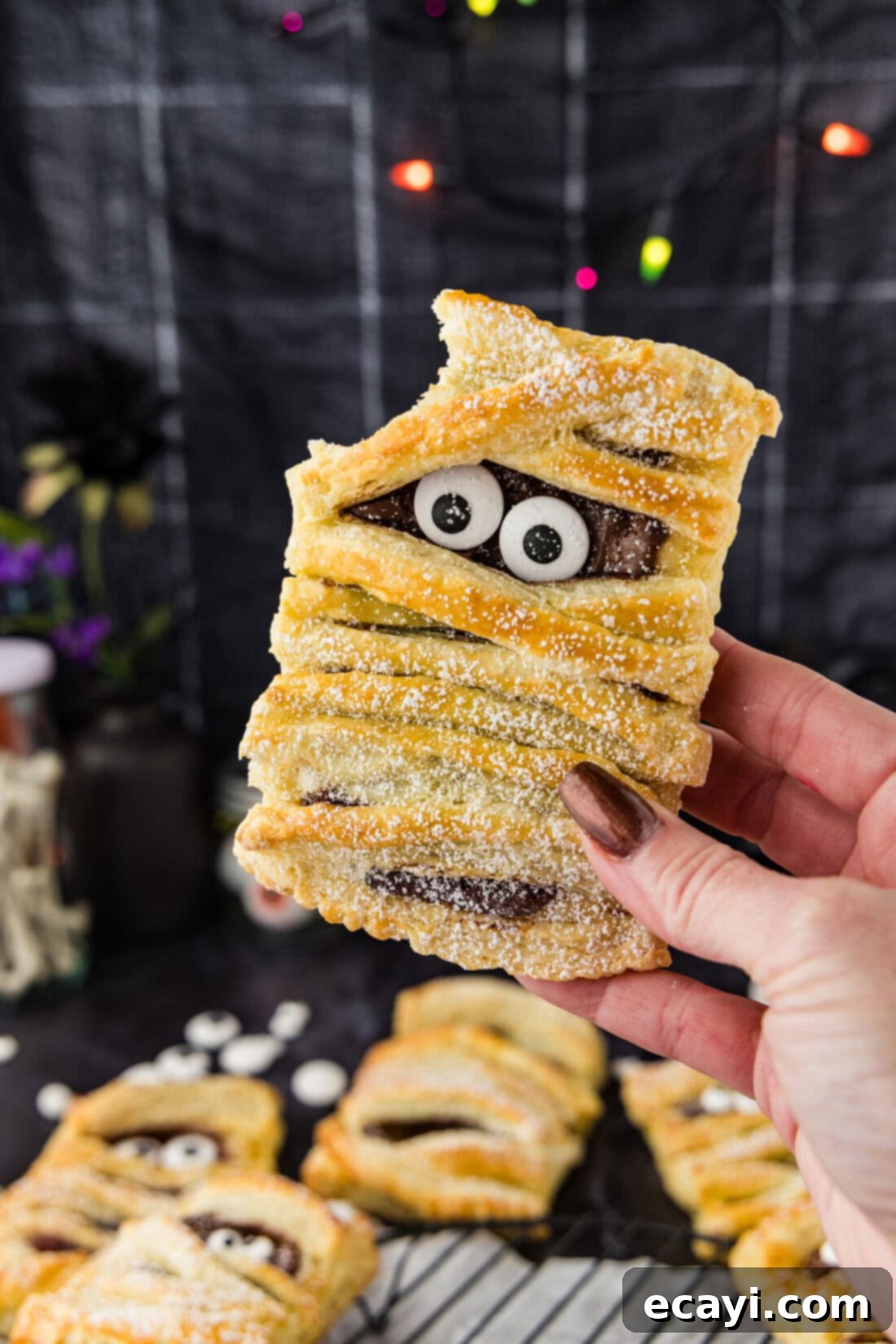 Halloween Mummy Bites 3 A hand holding a Mummy Hand Pie with a bite taken out, showing the sweet filling.