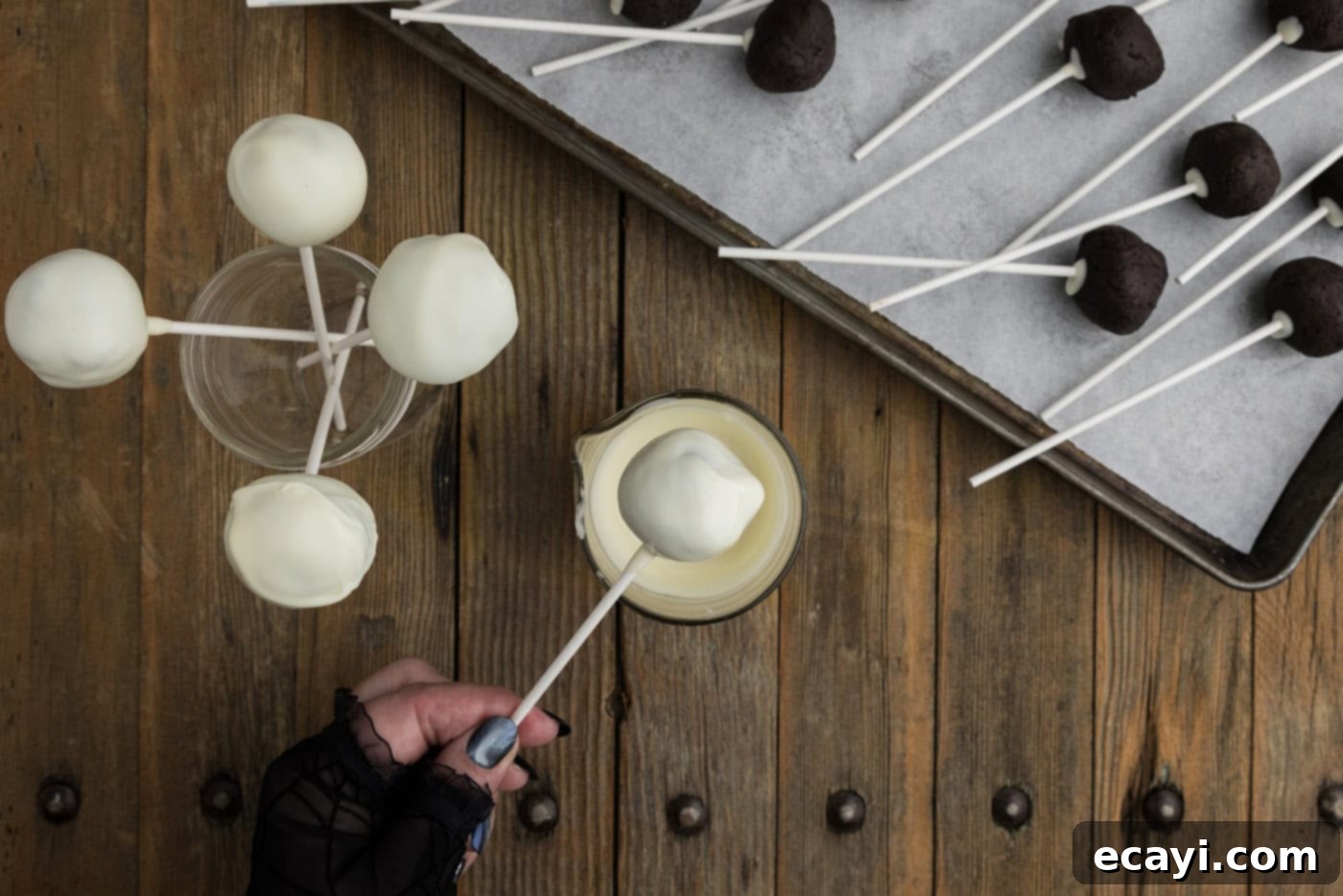 Pharaoh's Pops 11 Hand carefully dipping an Oreo truffle into smooth white chocolate coating, holding it by the lollipop stick