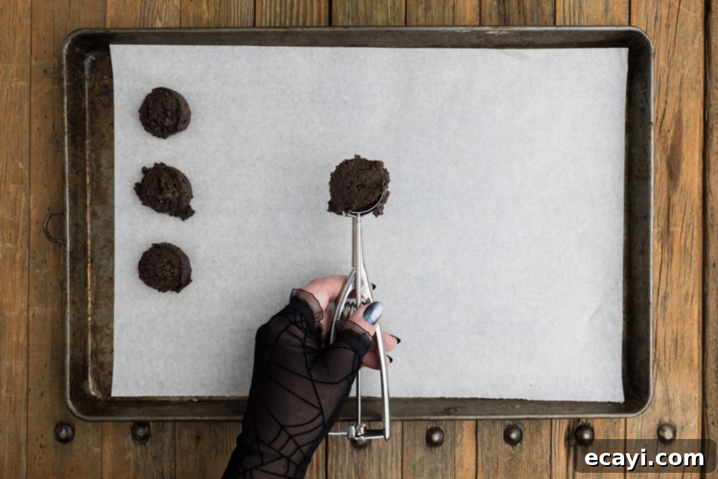Pharaoh's Pops 8 Tablespoon scoop of Oreo truffle mixture held over a parchment lined baking sheet, ready to be placed